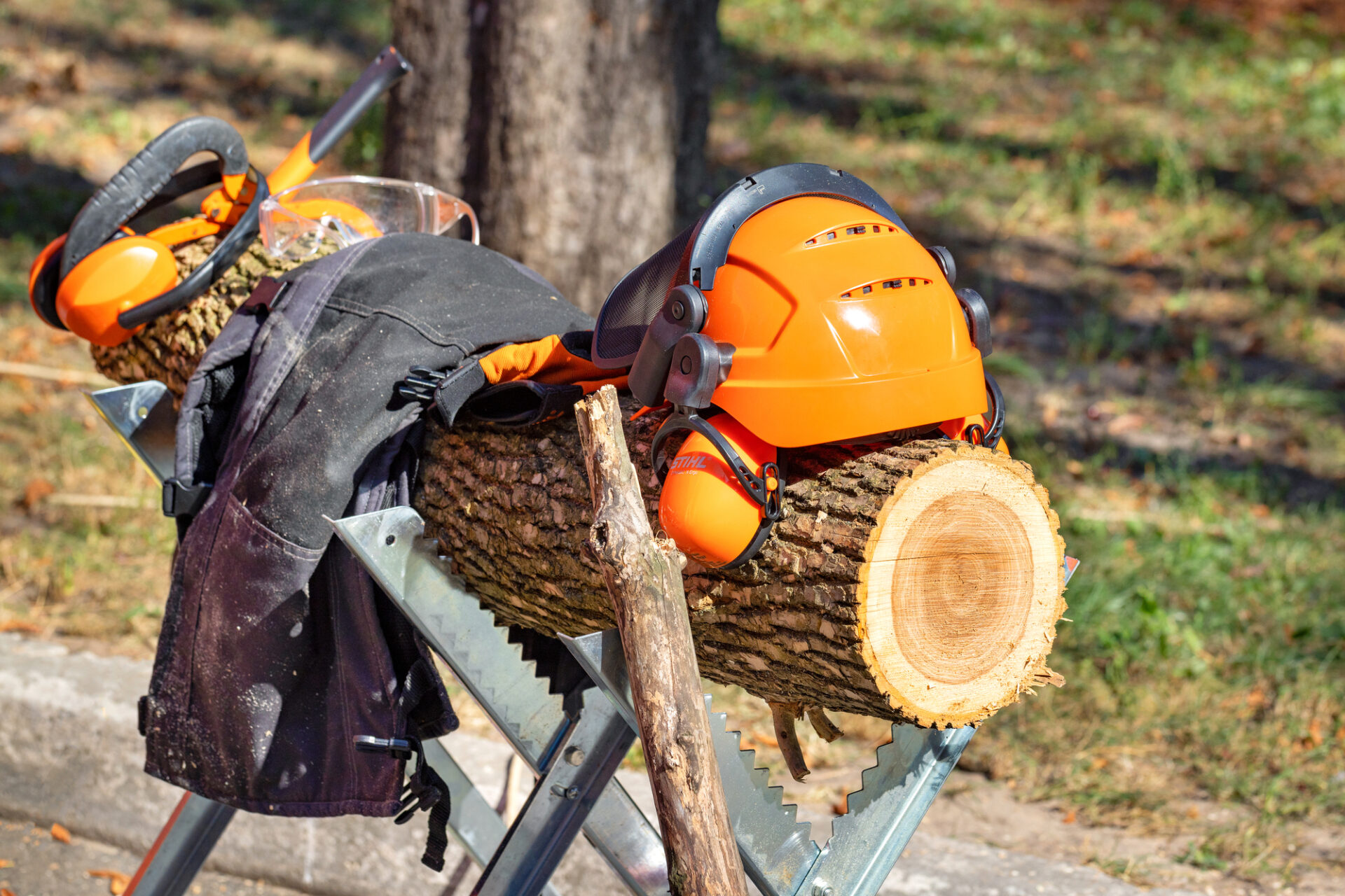 Protective helmet and overalls for a lumberjack from Stihl on a log with metal sawhorses. 09.26.23. Kyiv. Ukraine.